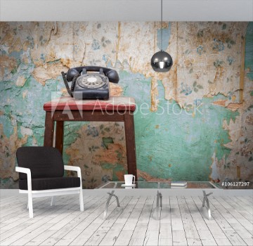 Picture of Old vintage phone on a chair stool in front of grunge wallpaper background